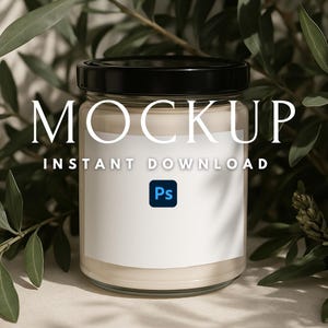 May include: A clear glass candle jar with a black lid and a white label that says "MOCKUP INSTANT DOWNLOAD" and a blue Photoshop icon. The jar is sitting on a beige surface with green leaves in the background.