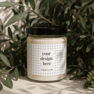 May include: A white candle in a clear glass jar with a black lid. The jar has a white label with a grid pattern and the text "your design here 2.8 in x 3.5 in".