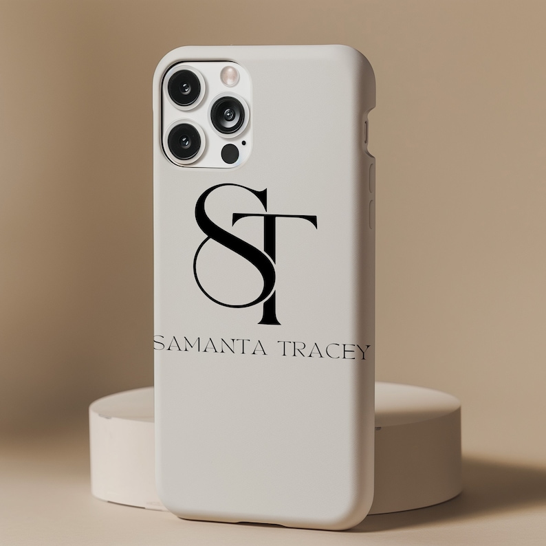 Pu&ograve; includere: Custodia per telefono bianca con un monogramma nero delle lettere "ST" e il testo "Samanta Tracey" sotto.