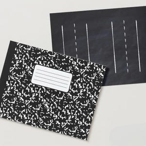 May include: A black and white composition notebook with a black chalkboard with white lines on top of it.