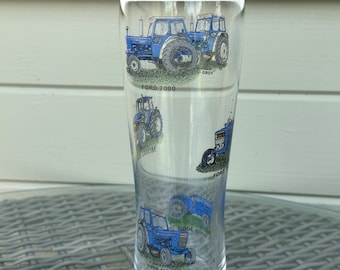Könnte beinhalten: Ein klares Glas mit einem blauen und weißen Design von Ford-Traktoren. Das Glas trägt die Aufschrift "Ford 7000", "Ford 4000", "Ford 6000" und "Cool Oldies".