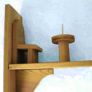 May include: Wooden wall mounted yarn holder with a shelf and a spindle. The spindle has a metal pin sticking out of the top.