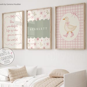 May include: Three framed prints with a nursery theme. One print has the text "How wonderful life is now you're in the world". Another has the name "SCARLETT". The third print features a duck wearing pink boots. All prints have a floral design.