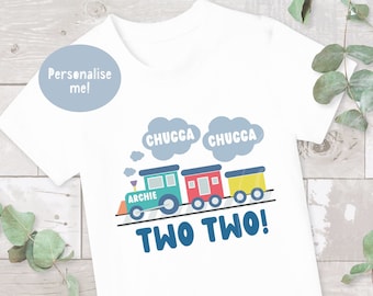 May include: White t-shirt featuring a blue train design. The train has a green engine with the word "Archie" on it and three colourful carriages. The text "Chugga Chugga Two Two!" is printed below the train.
