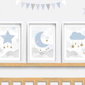 May include: Three framed prints in a blue and gold colour scheme. The prints feature a large blue star, a crescent moon, and a cloud with stars hanging from it. The prints are set against a white background and are displayed on a wooden shelf.