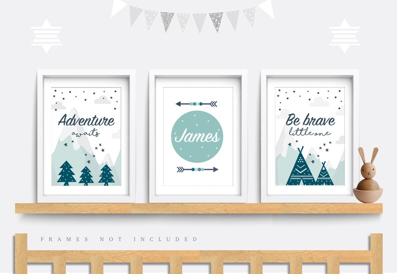 May include: Three framed prints with a woodland theme. The first print features a mountain range with trees and the text "Adventure awaits". The second print features a circle with the name "James" and arrows. The third print features a mountain range with teepees and the text "Be brave little one".
