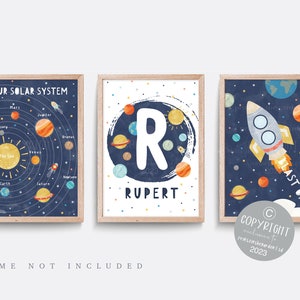 May include: Three framed prints with a space theme. One shows the solar system, another features the letter "R" and the name "Rupert", and the third depicts a rocket ship with the words "Last Off". The prints have a navy blue background with planets and stars.