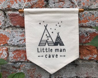 May include: A white canvas banner with black text and illustrations. The banner reads "Little man cave" and features two black and white teepees with stars above them.