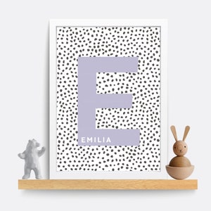 Puede incluir: Una impresi&oacute;n enmarcada en blanco con una letra E morada sobre un fondo blanco con lunares negros. El nombre Emilia est&aacute; escrito debajo de la letra.