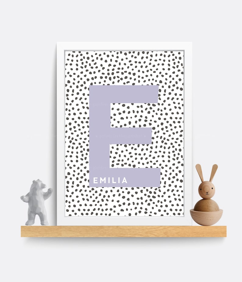Puede incluir: Una impresi&oacute;n enmarcada en blanco con una letra E morada sobre un fondo blanco con lunares negros. El nombre Emilia est&aacute; escrito debajo de la letra.