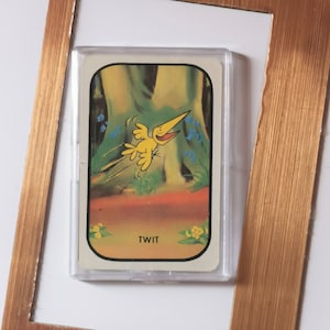 May include: A yellow bird with a long beak and a happy expression is flying through a forest. The card has the word "TWIT" printed on it.