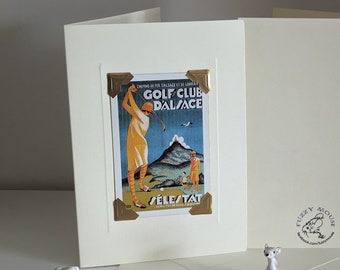 Op de afbeelding: Een witte kaart met een gouden rand en een vintage poster van een vrouw die golf speelt. De poster is voor de Golf Club Dalsace in Sélestat, Frankrijk. De kaart heeft een Fuzzy Mouse-logo op de achterkant.