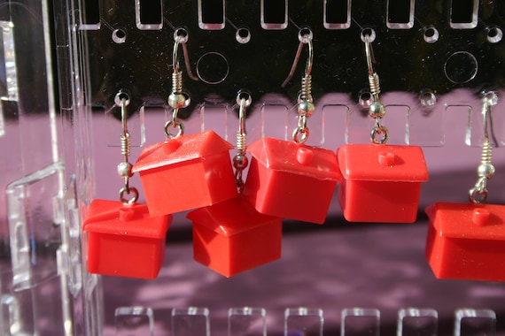 Real Monopoly hotel game pieces repurposed as earrings — tiny, nerdy, and delightfully absurd in a way no mass-produced jewelry brand would ever attempt.