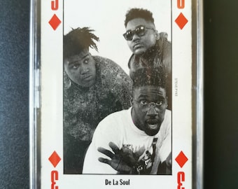 Op de afbeelding: Speelkaart met een zwart-wit foto van de hiphopgroep De La Soul. De kaart is een ruiten drie, met het nummer en symbool in rood. De kaart zit in een doorzichtige plastic hoes.