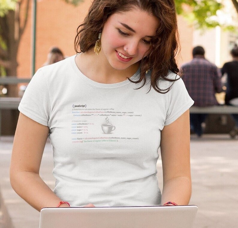 May include: A white t-shirt with a humorous graphic of JavaScript code that calculates the "flavor" of regular coffee. The code includes variables for coffee beans, water, sugar, and cream, and the result is a cup of coffee with steam rising from it.