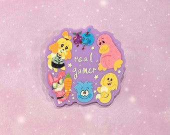 May include: A purple sticker with a cartoon illustration of a group of animal characters. The characters include a dog, a bunny, a bird, a blue creature, and a yellow creature. The text "real gamer" is written in the center of the sticker.