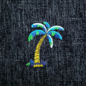 May include: A blue, green, and yellow embroidered palm tree patch. The palm tree is on a dark blue denim background.