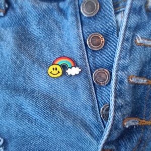 May include: A rainbow and smiley face embroidered patch on a blue denim jacket.