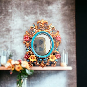 May include: A decorative mirror with a blue and gold frame. The frame is intricately carved with floral designs and painted with red, yellow, and orange accents.