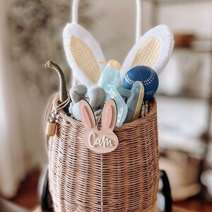 May include: A wicker basket with bunny ears, a wooden bunny tag with the name "Cam" and various toys inside.