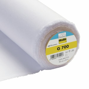 May include: A white roll of Vlieseline G 700 interfacing fabric. The label is yellow with black text and a barcode. The label says "100% BW/CO 90 cm x 25 m".