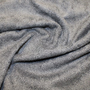 May include: Close-up of a soft, gray, textured fabric. The fabric is folded and wrinkled, showing its texture.