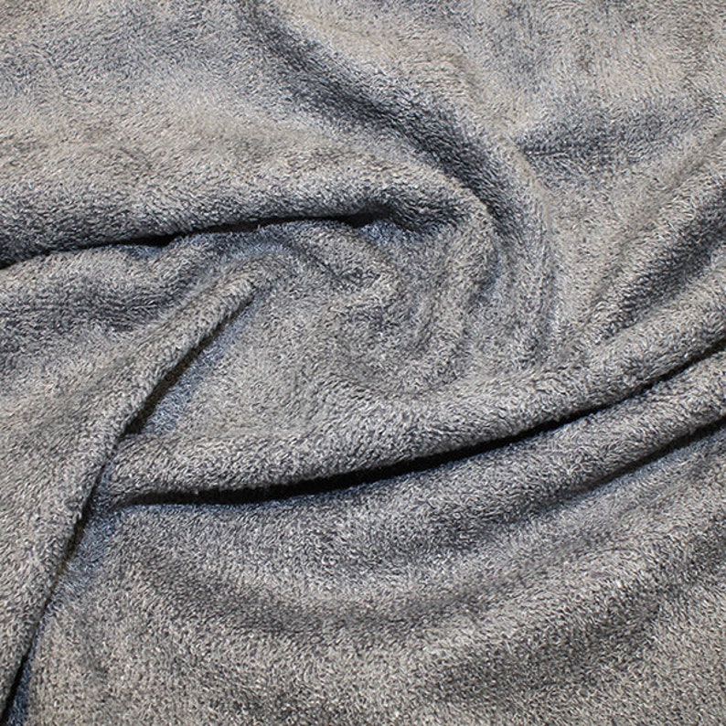 May include: Close-up of a soft, gray, textured fabric. The fabric is folded and wrinkled, showing its texture.