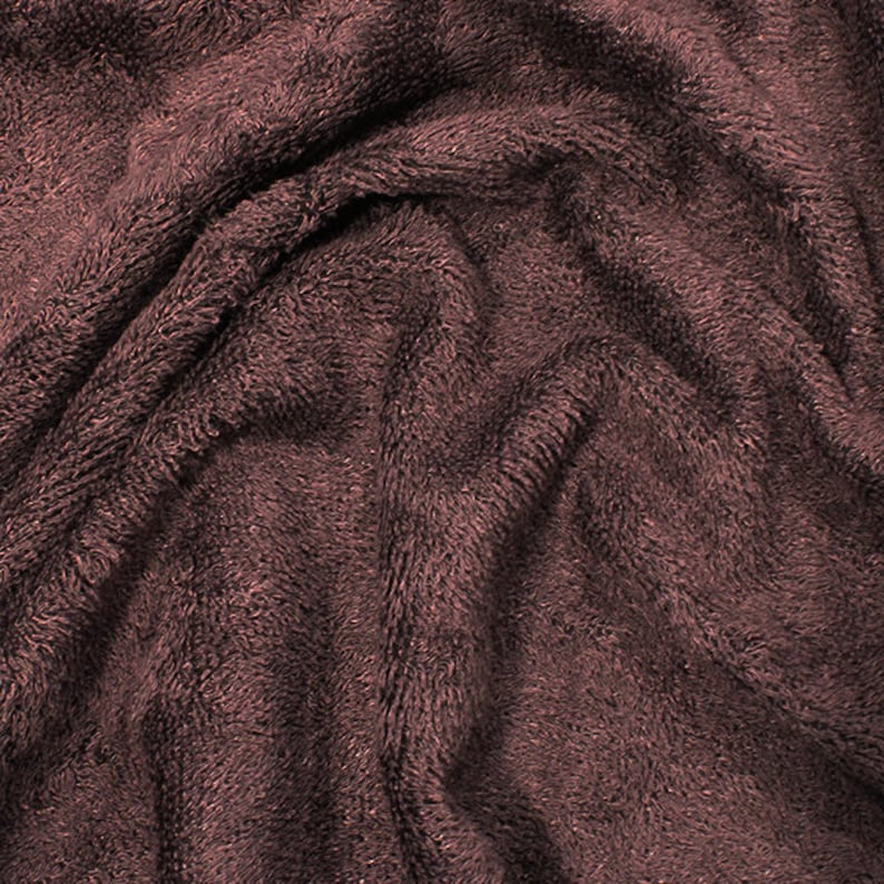 May include: Close-up of a soft, brown, plush fabric with a textured surface. The fabric is wrinkled and folded, creating a cozy and inviting look.
