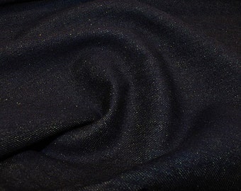 Op de afbeelding: Close-up van donkerblauwe denimstof met een subtiel sprankeleffect. De stof is gedrapeerd en toont plooien en texturen. De denim lijkt van hoge kwaliteit te zijn, met een lichte glans.