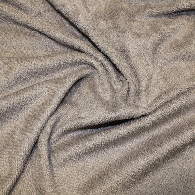 May include: Close-up of a soft, gray, plush fabric with a textured surface. The fabric is wrinkled and folded, showing its texture.