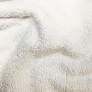 May include: Close-up of a white, fluffy towel with a soft, textured surface.