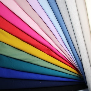 Puede incluir: Una colección de muestras de tela en varios colores, incluyendo rosa, rojo, amarillo, verde, azul y blanco. Las muestras están dispuestas en forma de abanico, con los colores más claros en la parte superior y los colores más oscuros en la parte inferior.