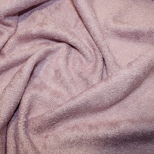 May include: A close-up of a soft, pink terry cloth fabric. The fabric is wrinkled and has a fuzzy texture.