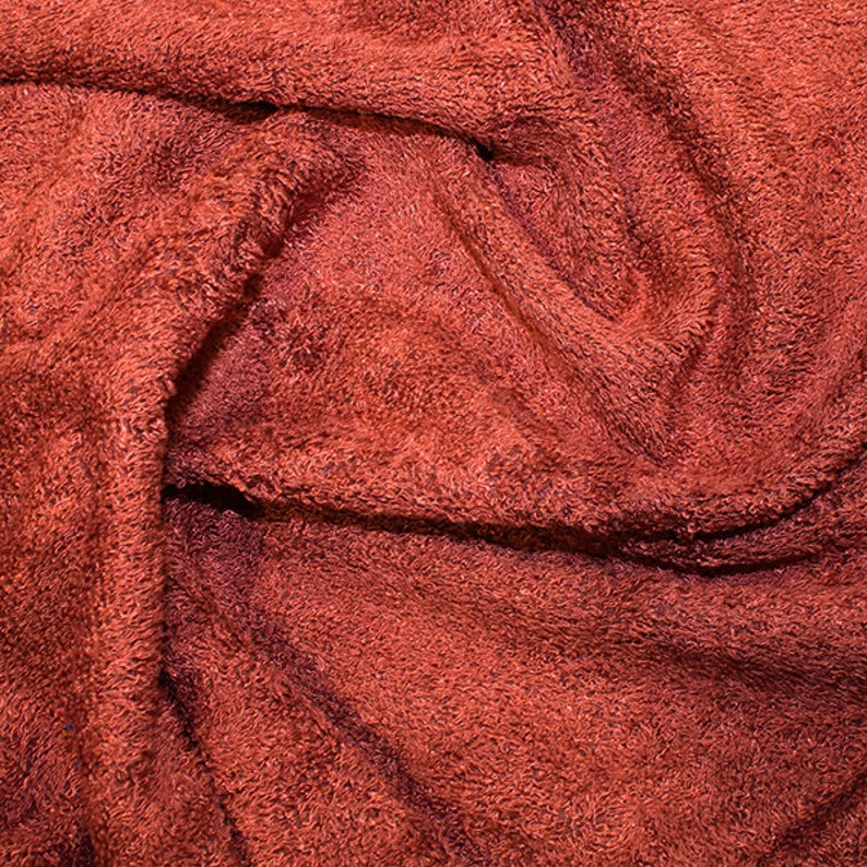 May include: Close-up of a red, textured fabric with a soft, fuzzy surface. The fabric is folded and wrinkled, creating a variety of textures and patterns.