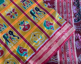 May include: A traditional Indian saree with a red and yellow checked pattern. The saree features intricate designs of elephants, peacocks, and floral motifs. The fabric is a blend of silk and cotton.