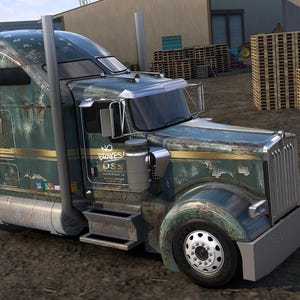 May include: A weathered, teal and gold semi-truck with the text "YARD DOG" spray-painted on the ground. The truck has a large cab, chrome accents, and a front bumper. Wooden pallets are stacked in the background.