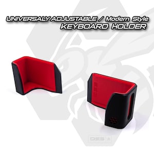 May include: Black keyboard on a rolling cart, with a red and black keyboard holder. The text reads "UNIVERSALLY ADJUSTABLE / Modern Style KEYBOARD HOLDER". The Key Keep logo is at the bottom.