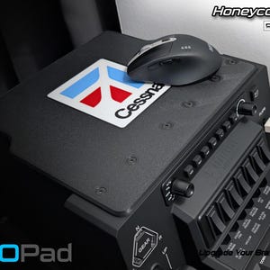 Peut inclure: Tapis de souris noir avec le logo Cessna et une souris d'ordinateur noire. Le tapis de souris fait partie d'un panneau de commande de simulateur de vol. Le texte sur l'image comprend "Honeycomb Bravo/Alpha MOUSE PAD" et "AEROPad".