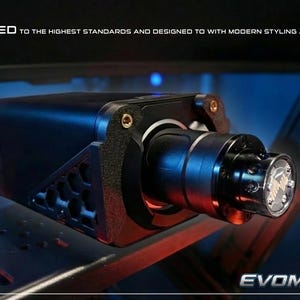 May include: A black 3D printed racing simulator steering wheel mount featuring a hexagonal side pattern and a cylindrical central hub. The text 3D PRINTED TO THE HIGHEST STANDARDS AND DESIGNED TO WITH MODERN STYLING AND FIT AND FINISH is visible.