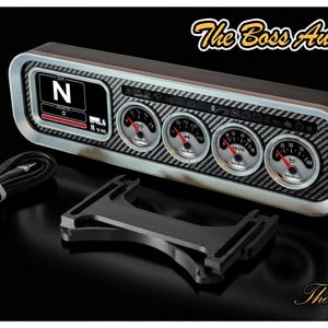 Puede incluir: Un grupo de indicadores automotrices negro y plateado con múltiples diales y una pantalla digital que muestra "N". Incluye un cable negro y un soporte de montaje. El texto "The Boss Aux Gauges" y "The Boss Hoss" son visibles.
