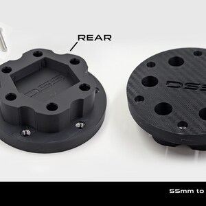 May include: Two black wheel adapters with the text "DSS" and "MOZA ES". The rear adapter has a unique shape, while the front adapter is round. Six M5x25mm screws are included. The text "55mm to UNIVERSAL 70 mm WHEEL ADAPTER" is also present.