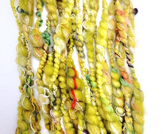 May include: A skein of hand-dyed yarn in a bright yellow-green color with white and multi-colored accents. The yarn is made of a blend of fibers, including wool, silk, and mohair.