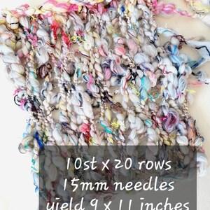 Op de afbeelding: Een kleurrijke gebreide stof met een witte basis en meerkleurige draden. De stof is 9 inch bij 11 inch en is gemaakt met 15 mm naalden. De tekst op de afbeelding luidt "10 st x 20 rijen 15 mm naalden opbrengst 9 x 11 inch".
