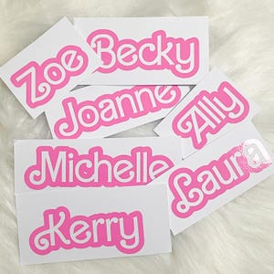 Puede incluir: Un conjunto de siete pegatinas de nombre personalizadas de color rosa y blanco con los nombres Zoe, Becky, Joanne, Ally, Michelle, Laura y Kerry.