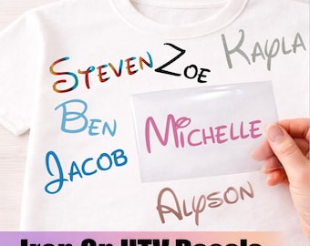 May include: A white t-shirt featuring various iron-on HTV decals with names including Steven, Zoe, Kayla, Ben, Jacob, and Alyson in different colors and fonts, with a clear transfer sheet displaying the name Michelle held over the shirt.