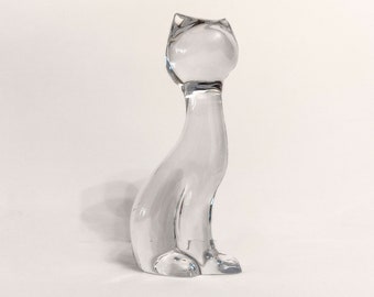 May include: A clear glass cat figurine. The cat is sitting with its head turned to the side.