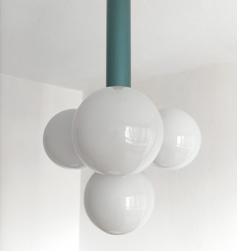 Puede incluir: Una l&aacute;mpara moderna con una varilla de metal turquesa y tres bombillas blancas en forma de globo.
