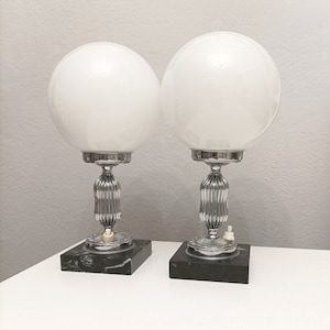 May include: Pair of vintage chrome table lamps with white glass globe shades and black marble bases.