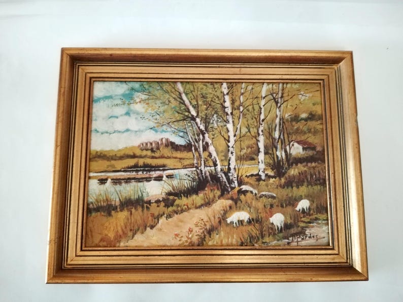 May include: A framed painting of a rural landscape with a river, trees, and sheep. The painting is done in a realistic style with muted colors.