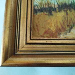 May include: A gold-colored picture frame with a black inner border. The frame is made of wood and has a slightly distressed finish.